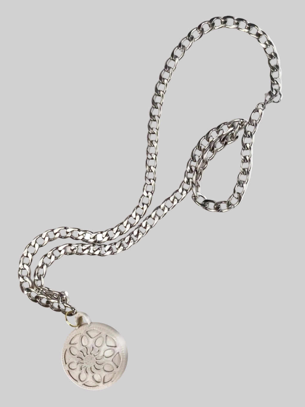 Silver chain necklace with a round pendant on a white background